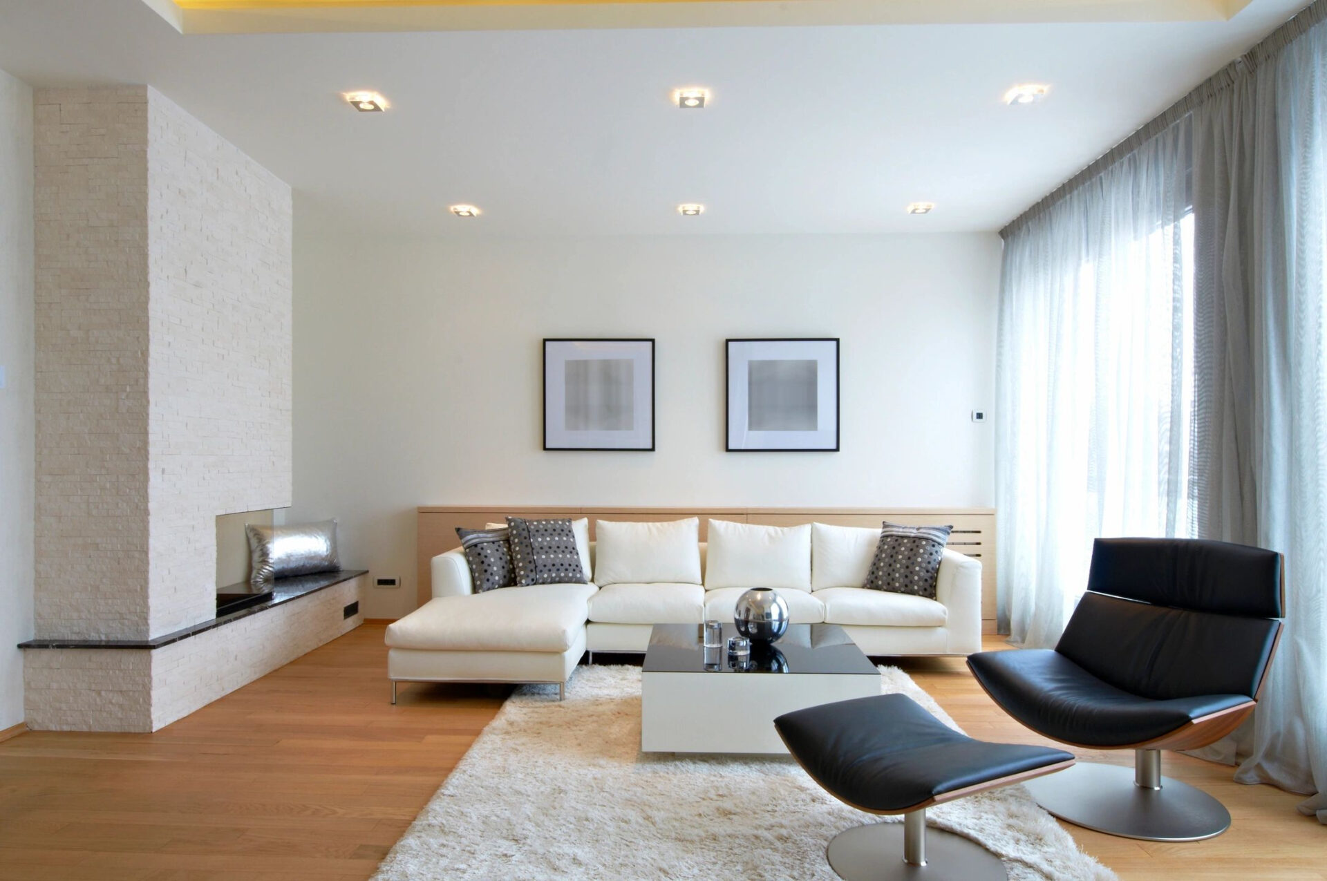 A living room with white furniture and wood floors.