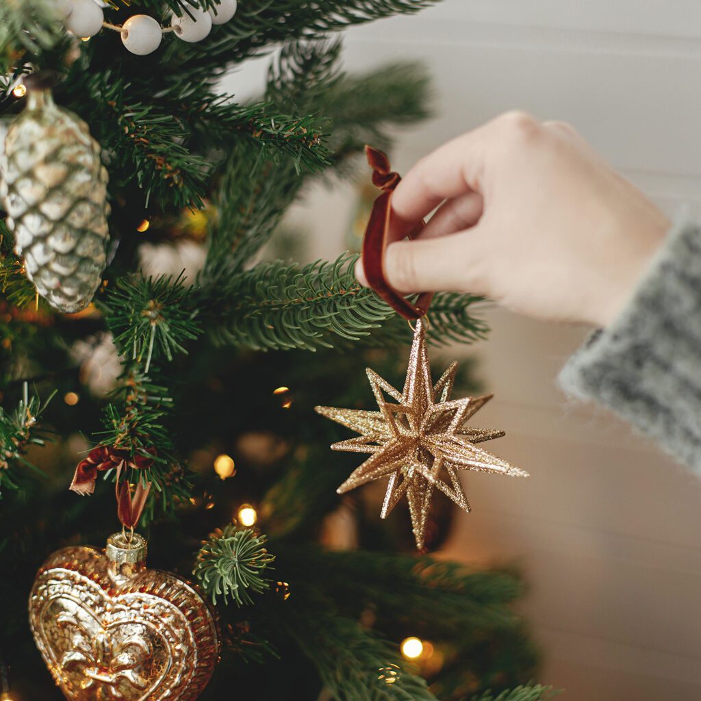 A person hanging ornaments on the christmas tree.