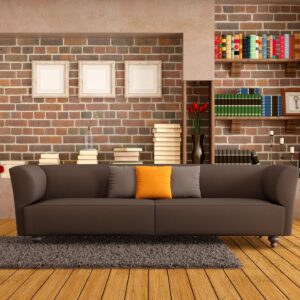 A couch in front of a brick wall with books on the shelves.