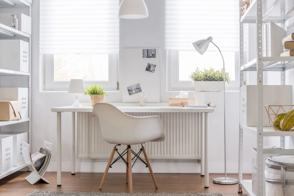 A white desk with a chair and lamp in front of it.