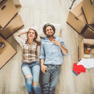 A man and woman laying on the floor in front of boxes.