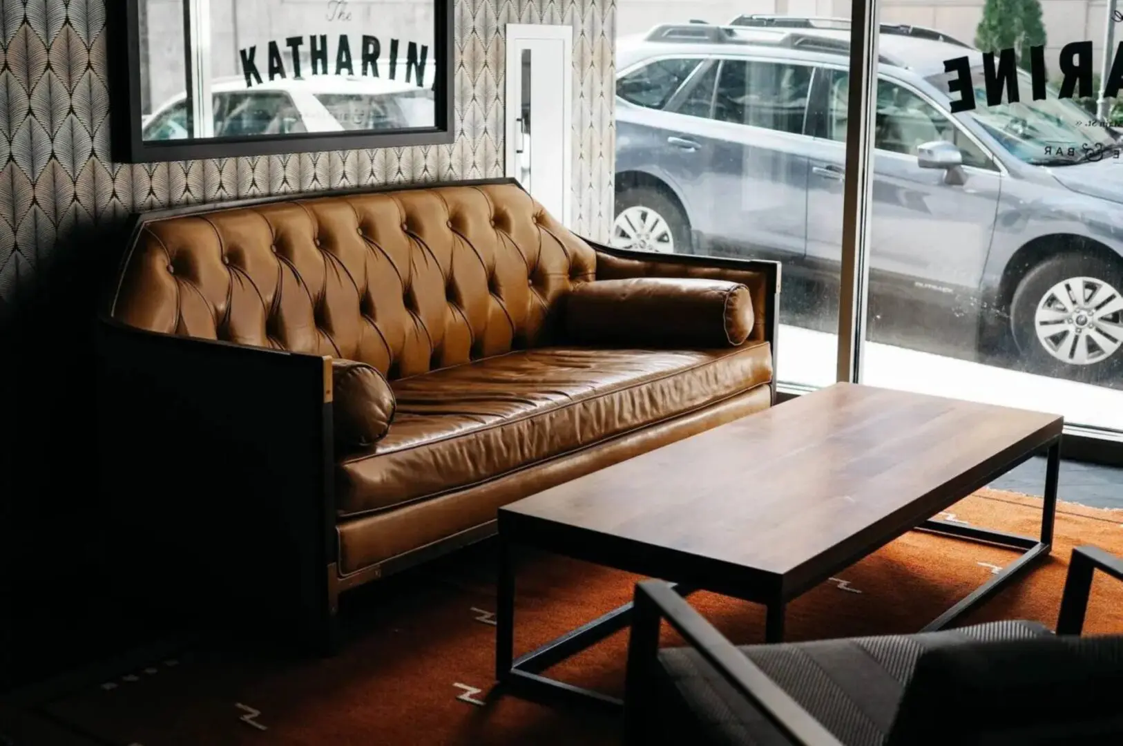 A brown leather couch in front of a window.